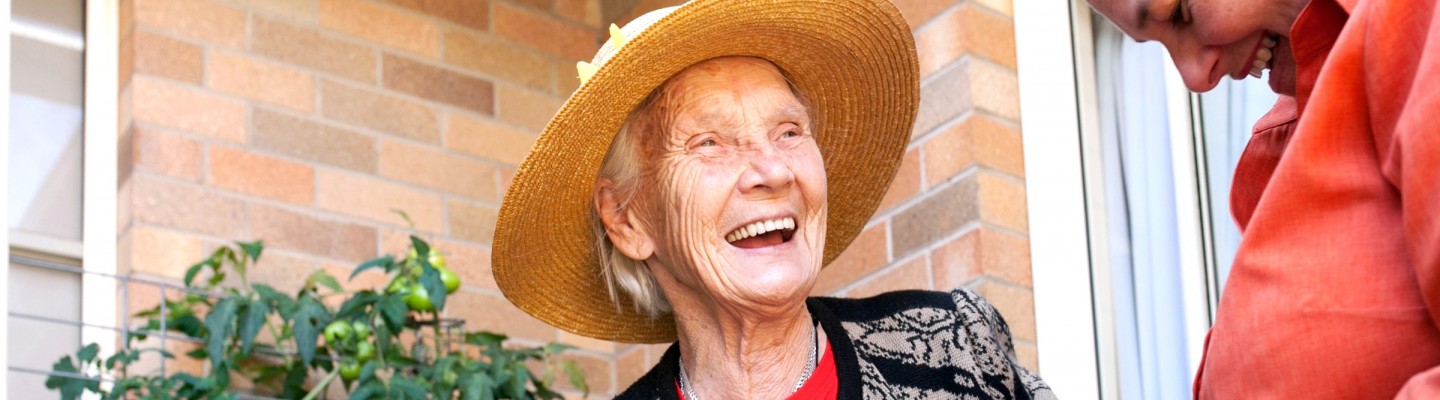 Elderly woman picking tomatoes with carer