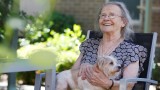 Smiling respite client holding a white and brown dog